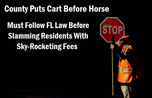 Worker holding stop sign with copy: County puts cart before horse
